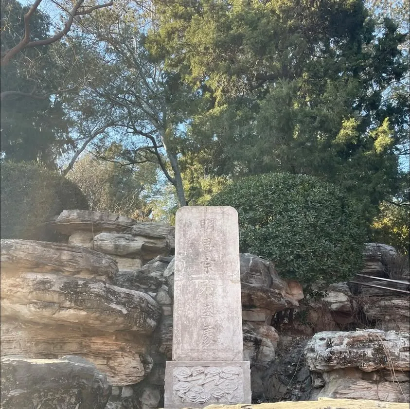 On the south slope of Jingshan Park, a stone tablet stands among rocks beneath the trees, inscribed "Where Emperor Sizong of Ming died for his country"
