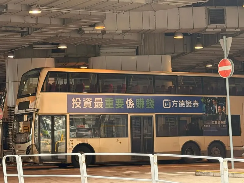 A Hong Kong double-decker bus carrying a brokerage ad that reads, in large Cantonese characters, "The most important thing about investing is making money"