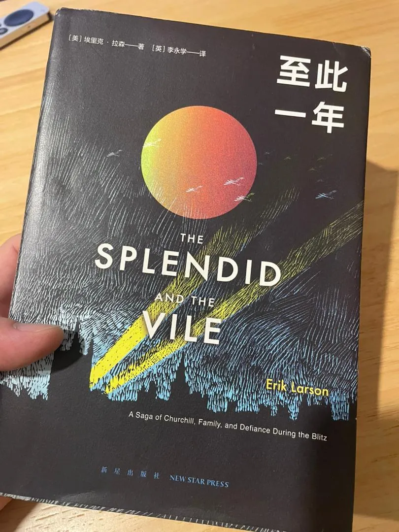 Gary 手里拿着 Erik Larson《至此一年》(The Splendid and the Vile)的中文版,封面是一轮红日和划过夜空的探照灯,背景是木桌