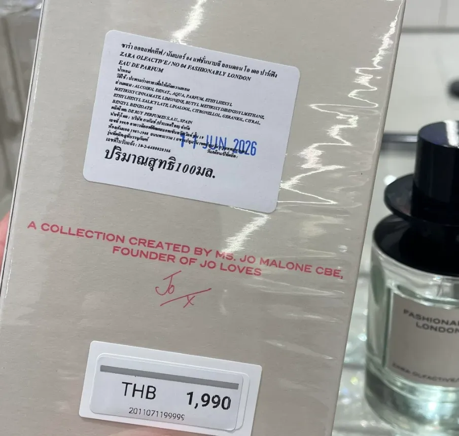 The back of a ZARA perfume box reading "A collection created by Ms. Jo Malone CBE, founder of Jo Loves", next to a bottle of Fashionably London